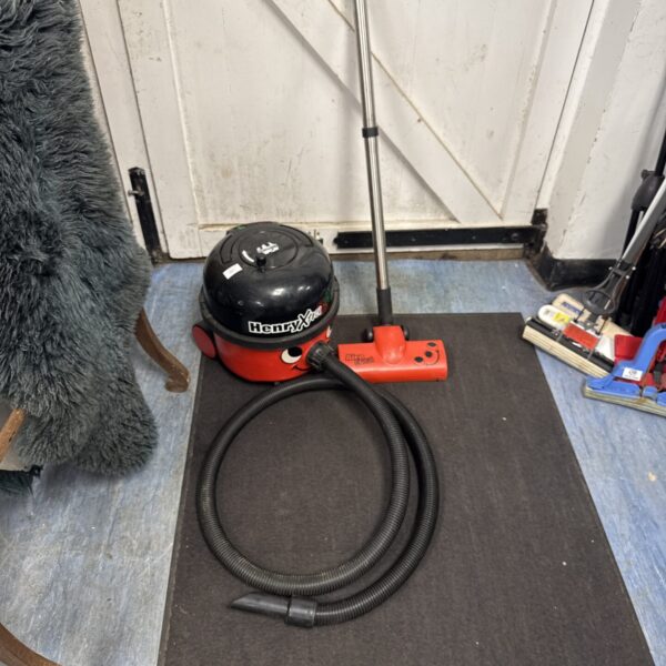 Red Numatic Henry Hoover vacuum cleaner with hose.