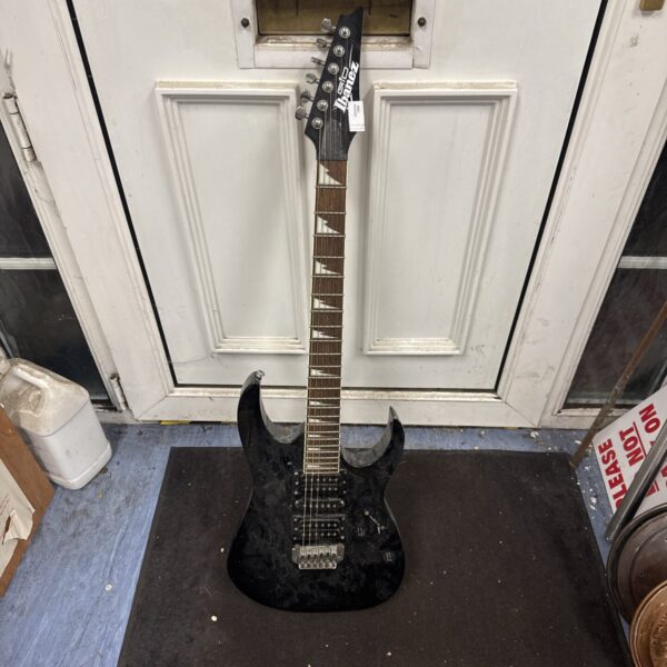 Black Ibanez Gio electric guitar with visible wear and tear.