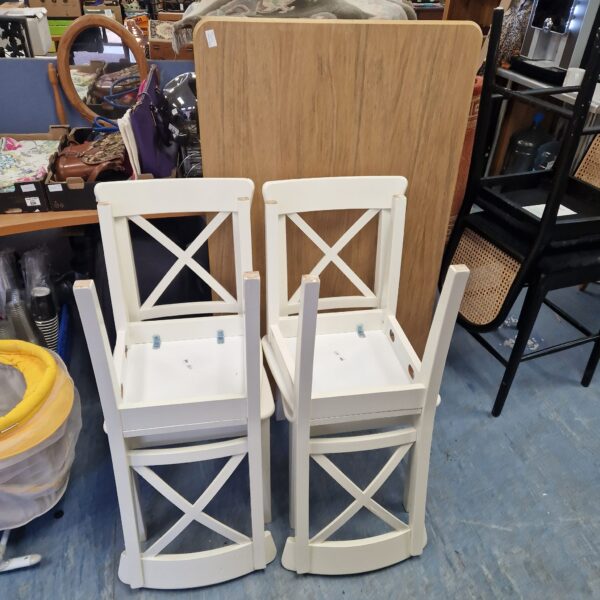 White Ikea dining chairs with spindle backs in a farmhouse style.
