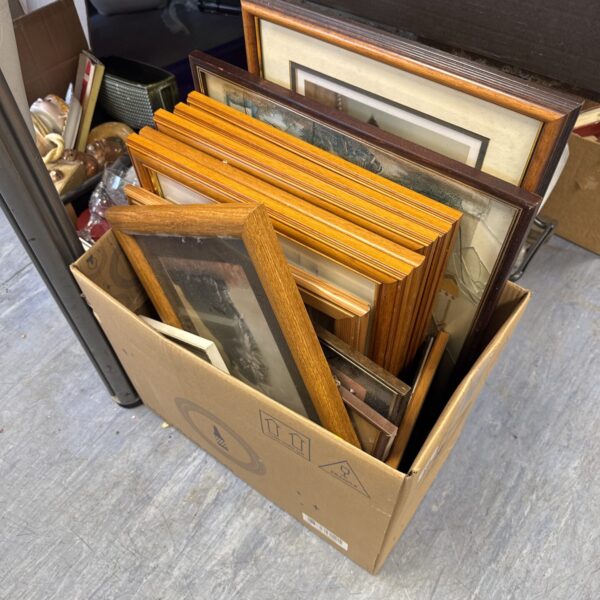 Box filled with assorted framed artworks and vintage prints.