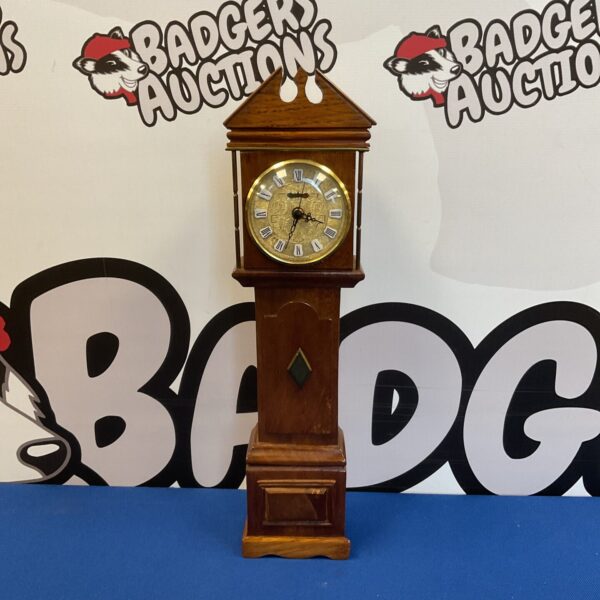 Front view of a miniature grandfather clock with a white face.