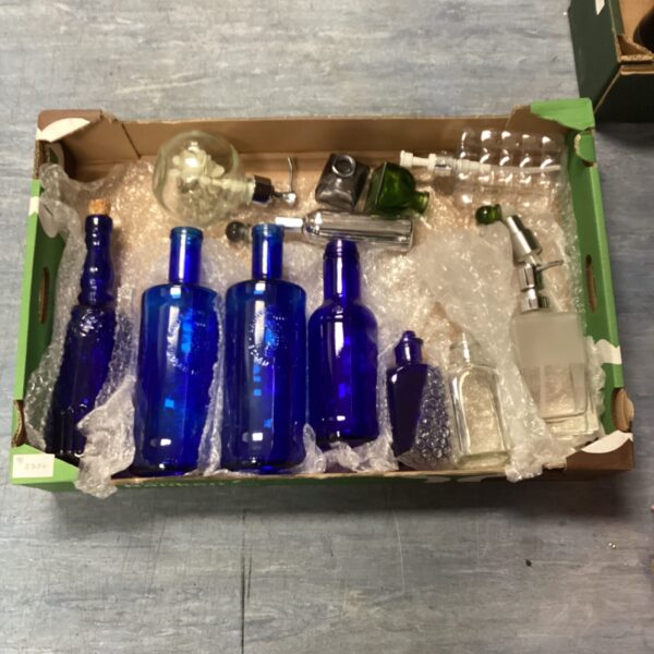 Vintage coloured bottles displayed in a cardboard box.
