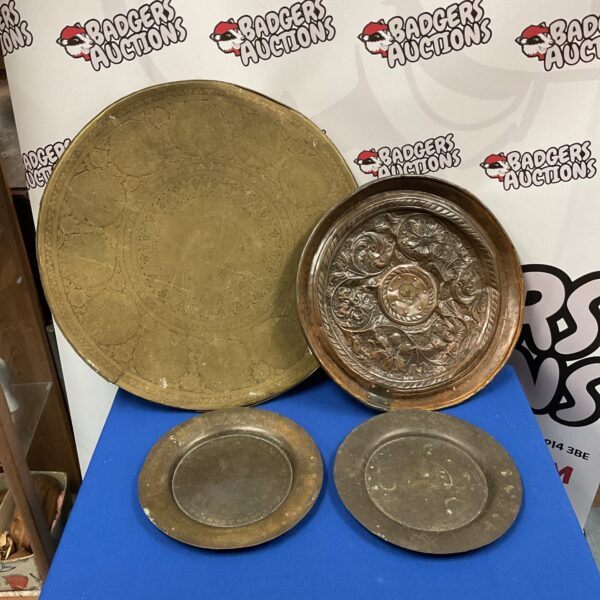 Vintage brass and copper chargers displayed together.