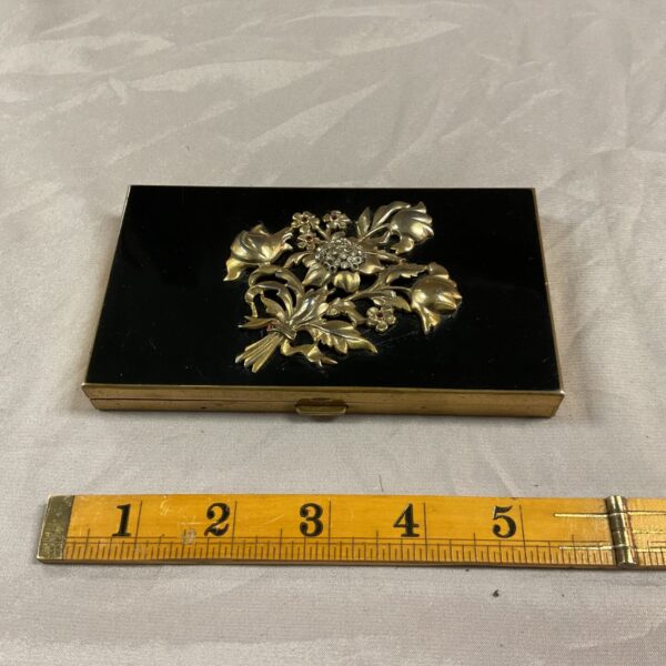 Vintage powder compact with floral design and velvet interior.