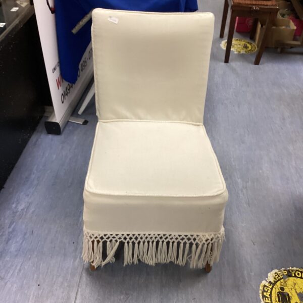 Vintage cream nursery chair with fringed detail.
