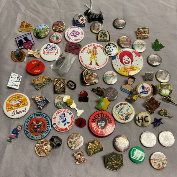 Vintage pinback button collection with advertising and music themes.