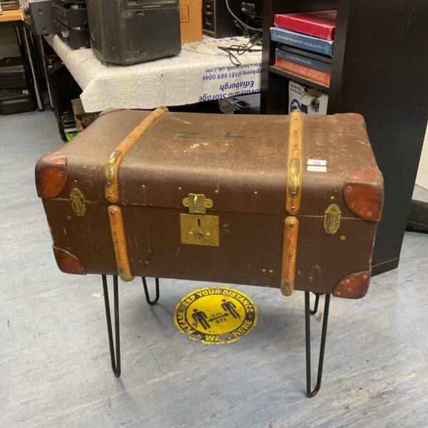 Vintage travel trunk table with metal legs, retro storage.