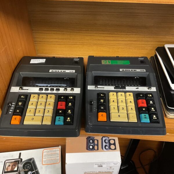 Two vintage Adler 1216 calculators on a wooden surface.