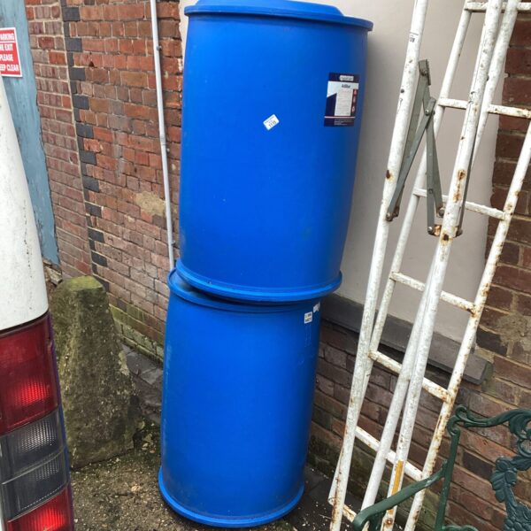 Two blue plastic water drums for garden storage.