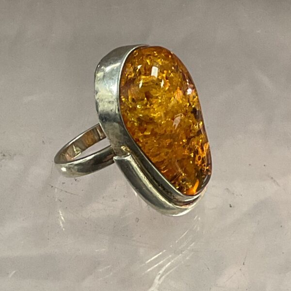 Close-up of a silver ring with orange amber gemstone.