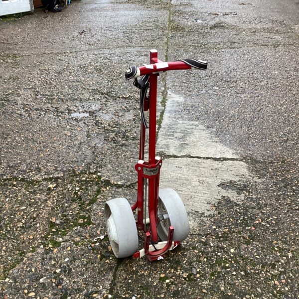 Red vintage Titleist golf trolley with three wheels.