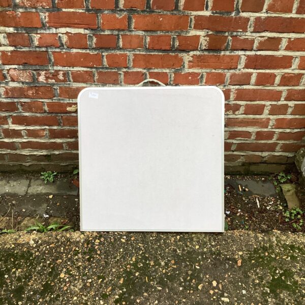 White plastic folding camping table, showing signs of wear.