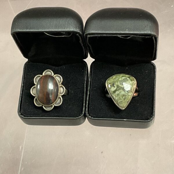 Close-up of silver rings with dendritic opal and brown jasper gemstones.