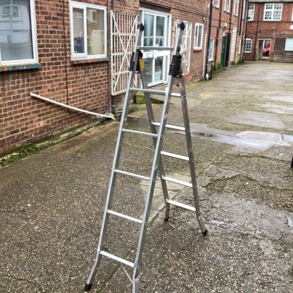 Silver aluminium combination ladder leaning against a brick wall.