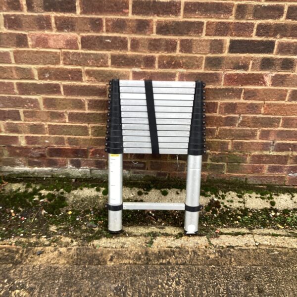 Silver aluminium telescopic ladder extended against a brick wall.