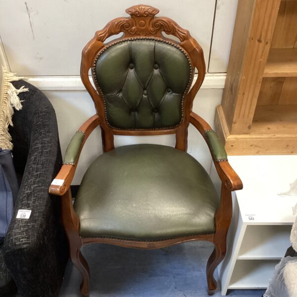 Vintage green leather armchair with carved wooden frame.