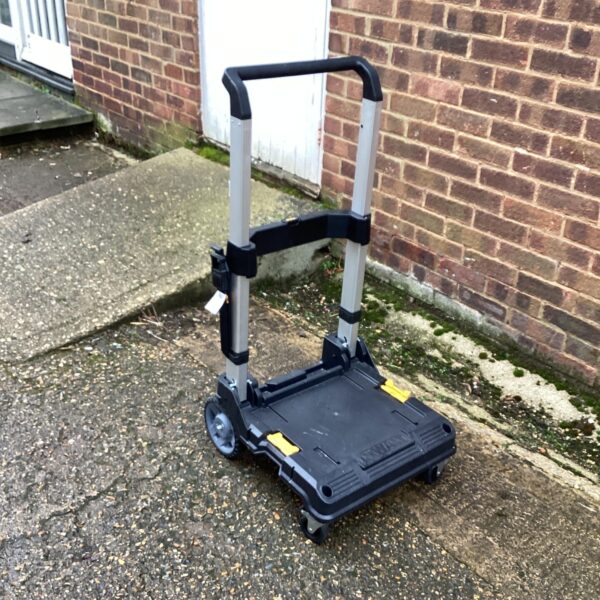 Black and yellow DeWalt folding work trolley on a paved surface.