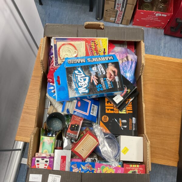 Assorted vintage magic toys and trick sets in a cardboard box.