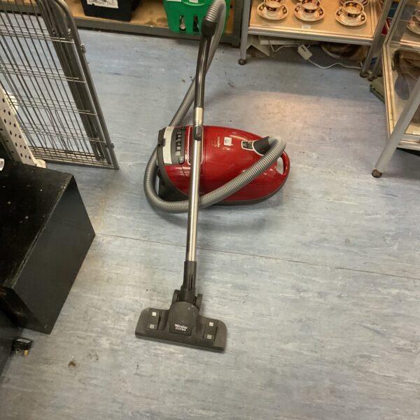 Red Miele C3 cylinder vacuum cleaner for home floor cleaning.