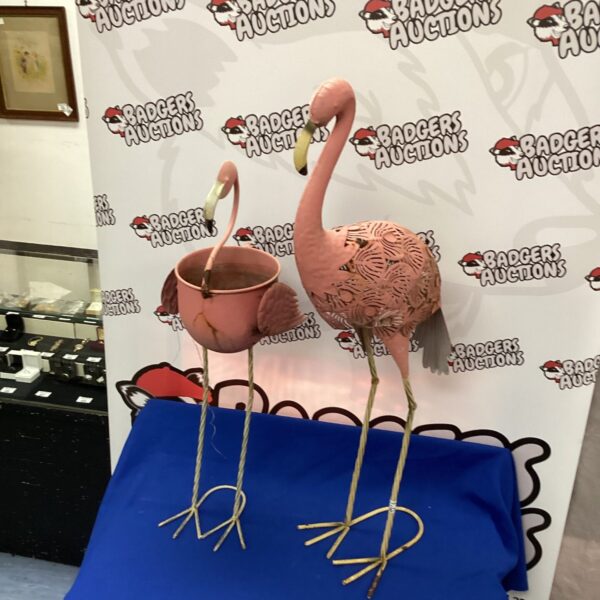 Two vintage metal flamingo garden ornaments on display.