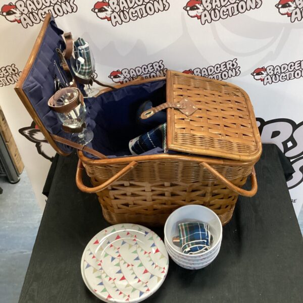 Vintage picnic basket with enamelware plates and cutlery.
