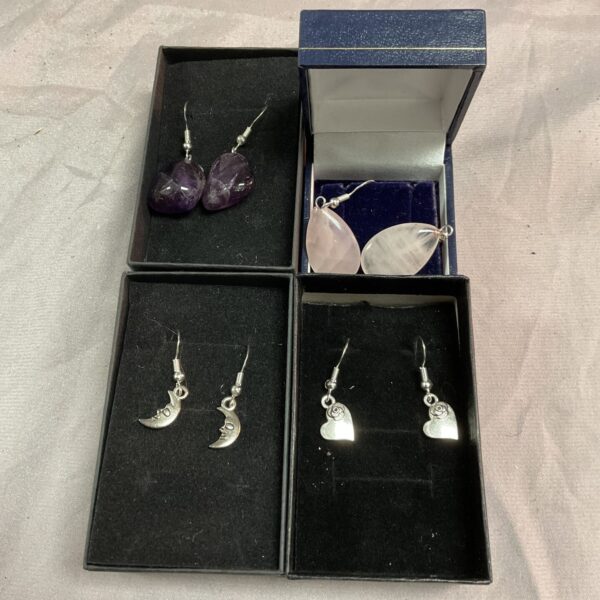 Close-up of silver earrings with amethyst-coloured stones.