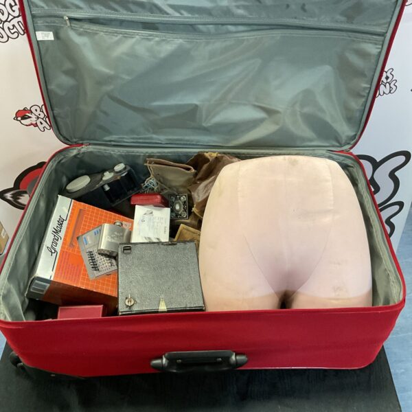 Red travel case filled with a vintage chess set and mannequin waist.