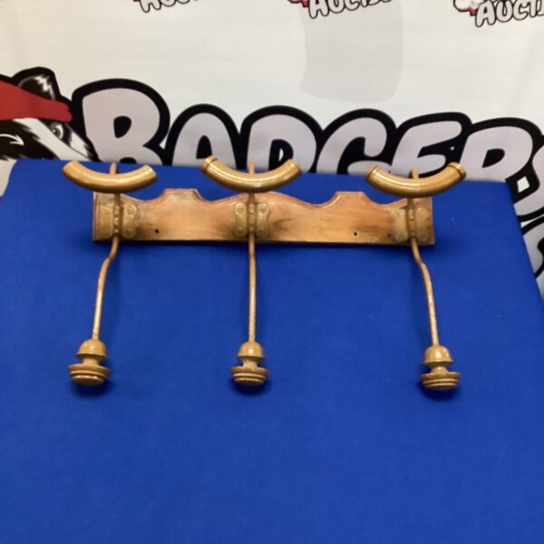 Vintage brass coat hooks mounted on a wall.