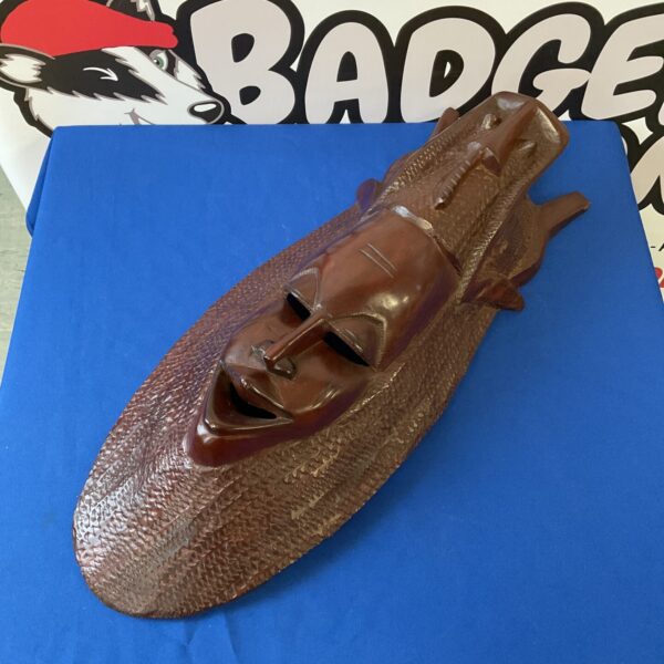 Large carved wooden African mask with detailed facial features.