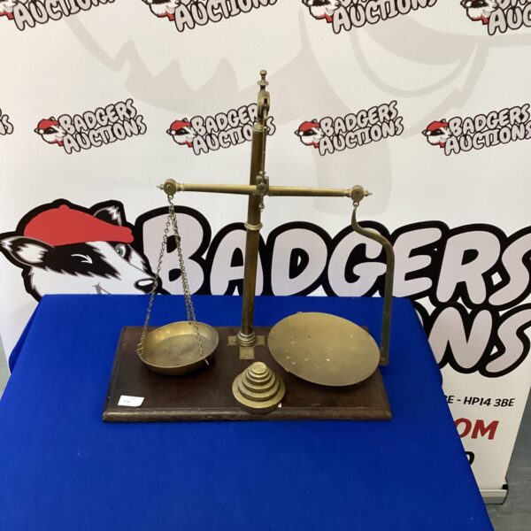 Vintage brass scales with weights on a dark surface.