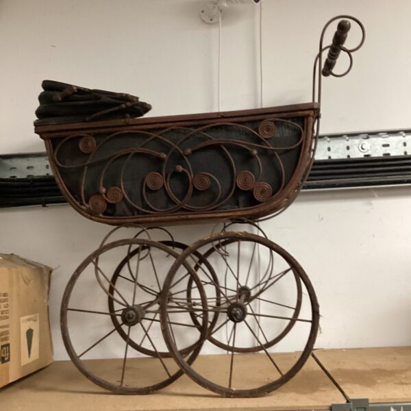 Vintage ornamental pram with spoked wheels, a charming antique carriage.