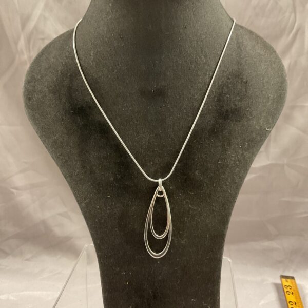 Silver pendant necklace displayed on a black mannequin bust.