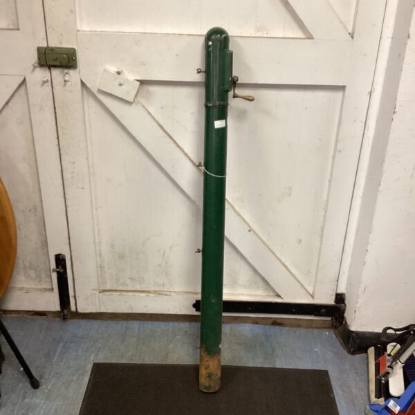Vintage tennis net post against a wooden wall.