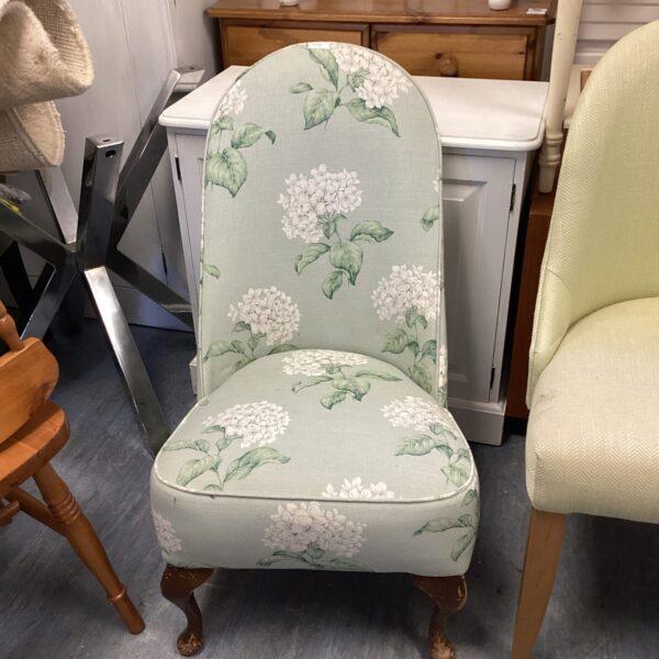 Vintage floral slipper chair with turned legs and patterned upholstery.