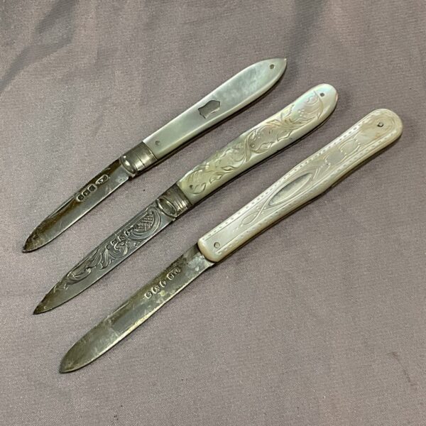Antique silver fruit knives with iridescent mother of pearl handles.