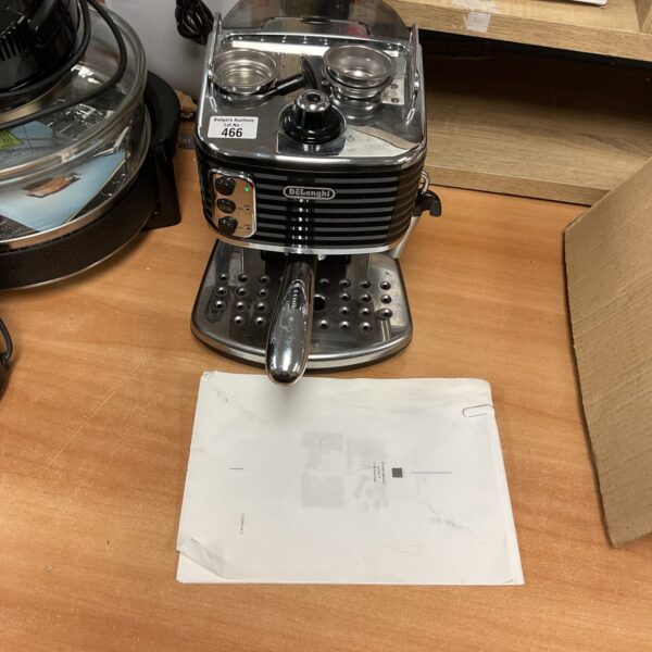 Front view of a used DeLonghi coffee machine with attachments.