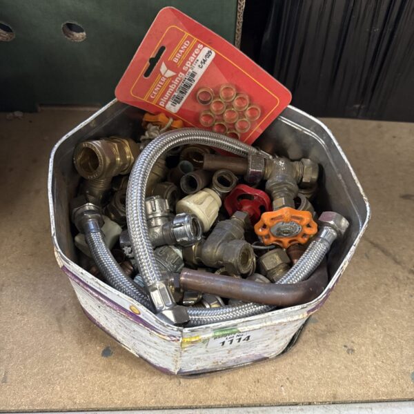 Assorted brass plumbing fittings inside a vintage Quality Street tin.