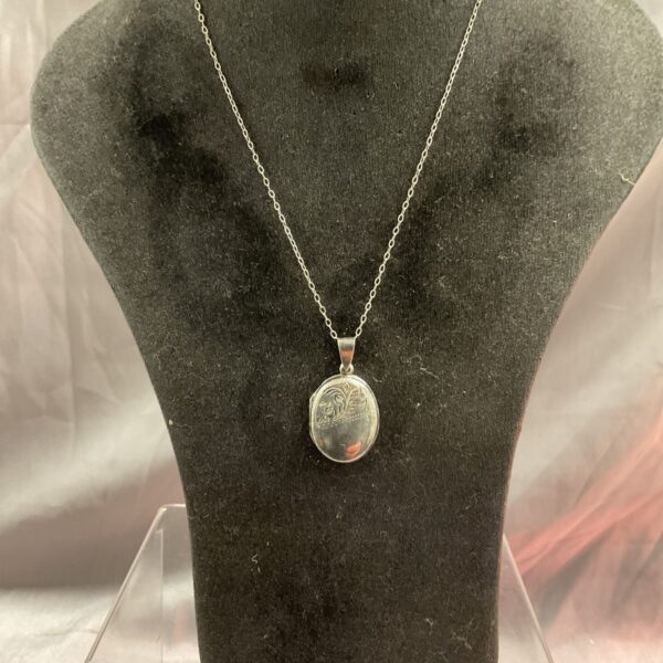 Vintage silver heart locket necklace on a chain.