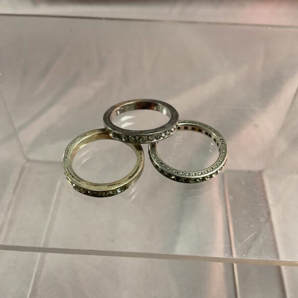 Close-up of three stoneset rings in silver tone.