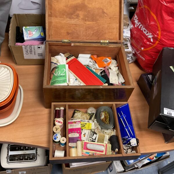 Vintage wooden sewing box filled with sewing supplies and notions.