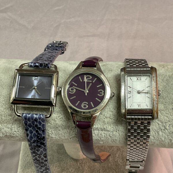 Lot of three ladies quartz wristwatches in silver, purple, and gold.