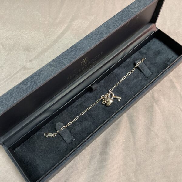 Delicate silver charm bracelet with heart and key.