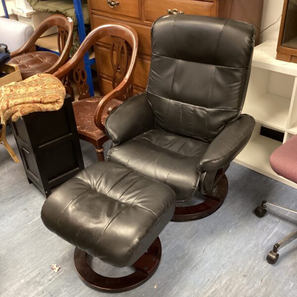 Black leather swivel chair with footrest in a home setting.