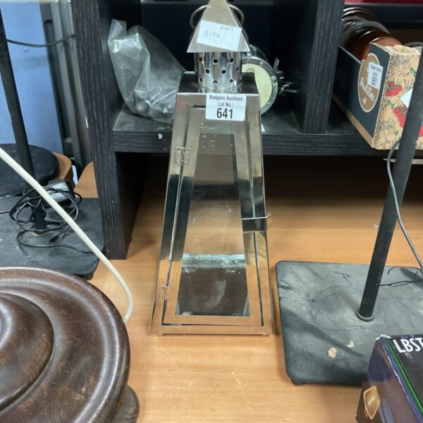 Polished stainless steel candle lantern with modern design.