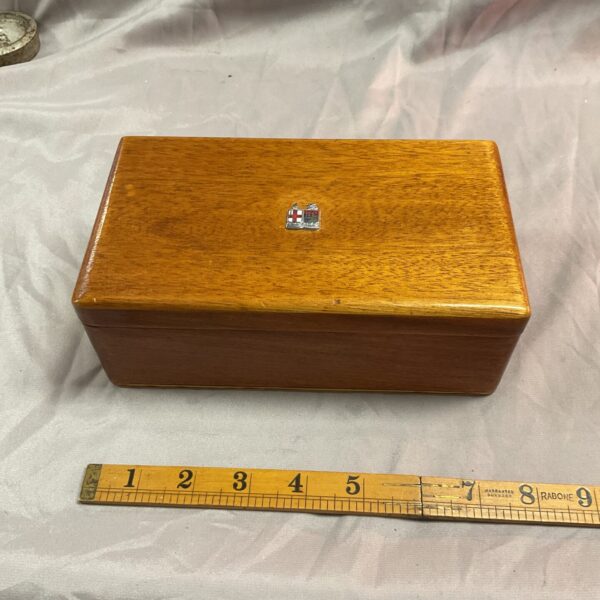 Vintage wooden trinket box with felt lining and decorative emblem.