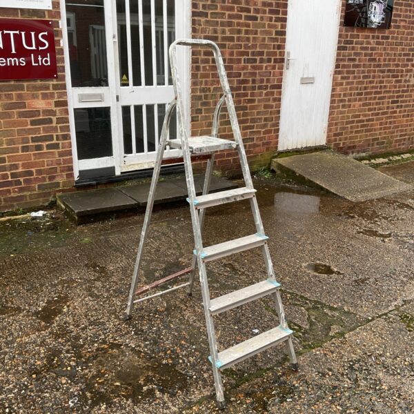 Silver aluminium five-step ladder against a brick wall.