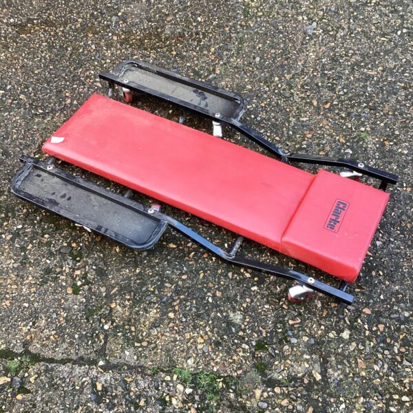 Padded Clarke mechanics trolley for automotive repairs in a garage.