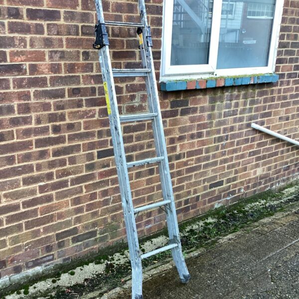 Silver multi-purpose aluminium ladder leaning against a brick wall.