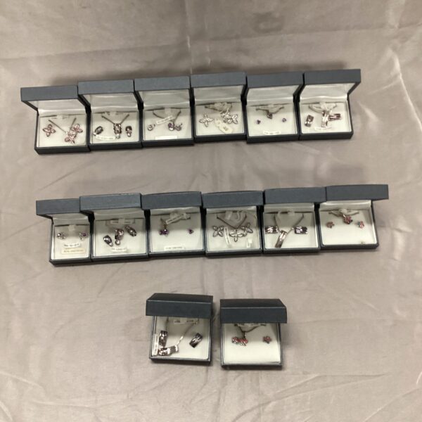 Lot of fourteen sterling silver necklace and earring sets displayed.
