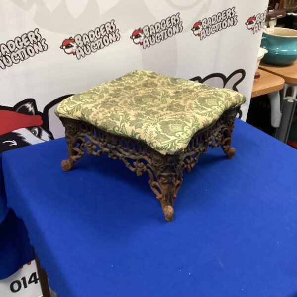 Ornate Victorian cast iron footstool with patterned upholstery.